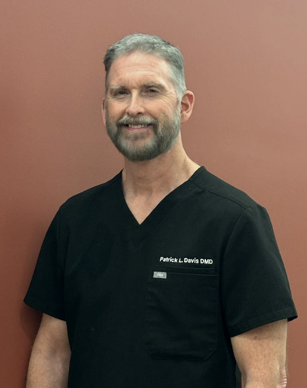 Dentist Northport AL Patrick Davis About Us HPH Dentist, Dr. Patrick Davis DMD, posing in front of a red wall for a photograph smiling warmly