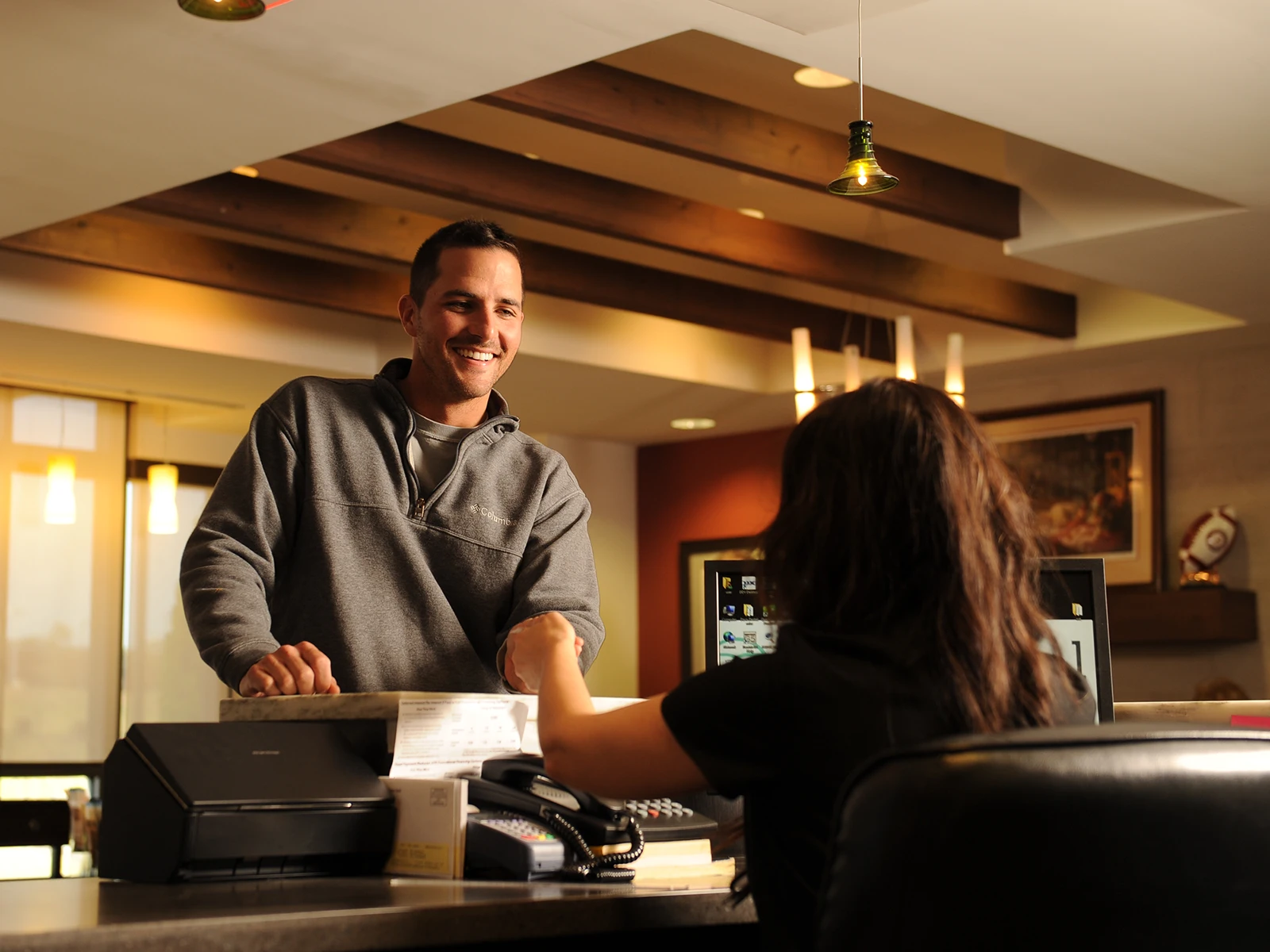Photo of smiling patient checking in for his appointment at the front desk