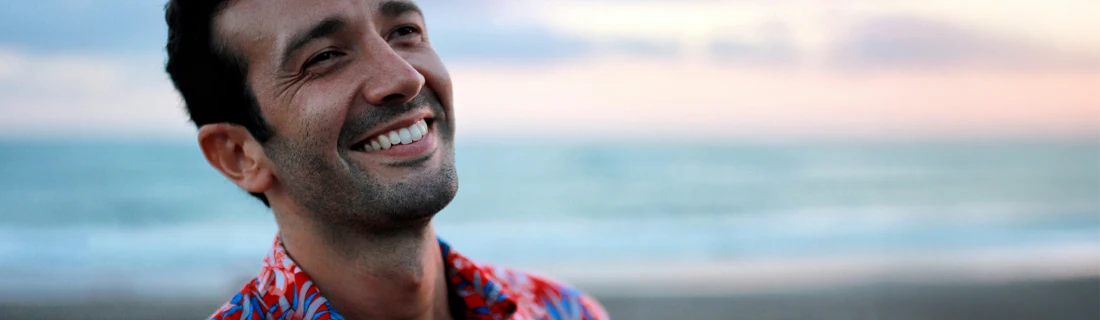 Dentist Tuscaloosa AL Cosmetic Dentistry Focused attractive man with a light beard is smiling while walking on the beach
