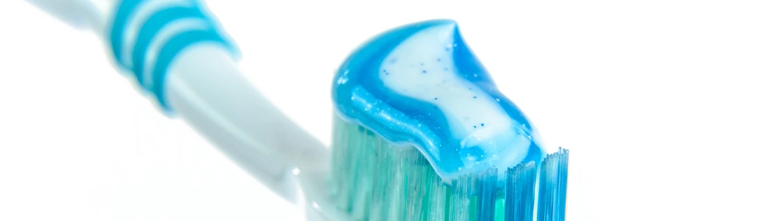 Dentist Tuscaloosa AL General Dentistry Focused a blue-green toothbrush is seen with a generous squirt of blue toothpaste on the bristles